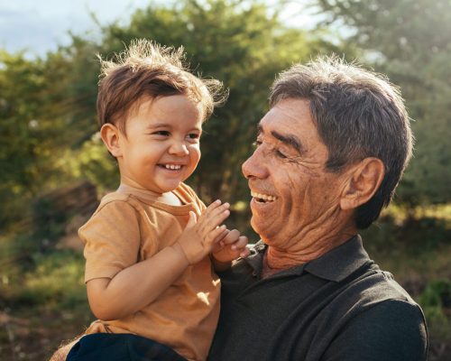 Playful grandfather spending time with his grandson in park on sunny day